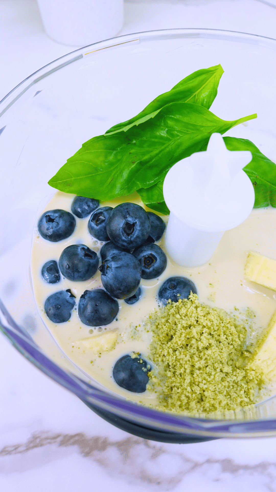 Ready to blend smoothie of blueberries, bananas and basil leaves