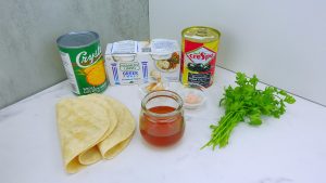 Another view of taco salad ingredients and dressing components on a table.