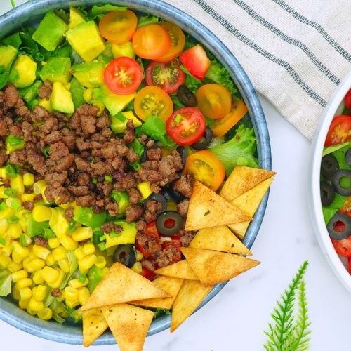 Serving taco salad with creamy dressing in a white bowl.