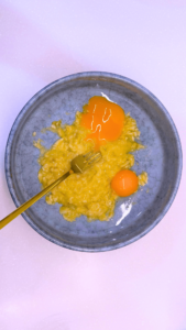 Adding egg yolks to mashed bananas for pancake batter.