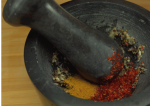 Adding fresh thyme, turmeric, and hot pepper flakes to the mortar.