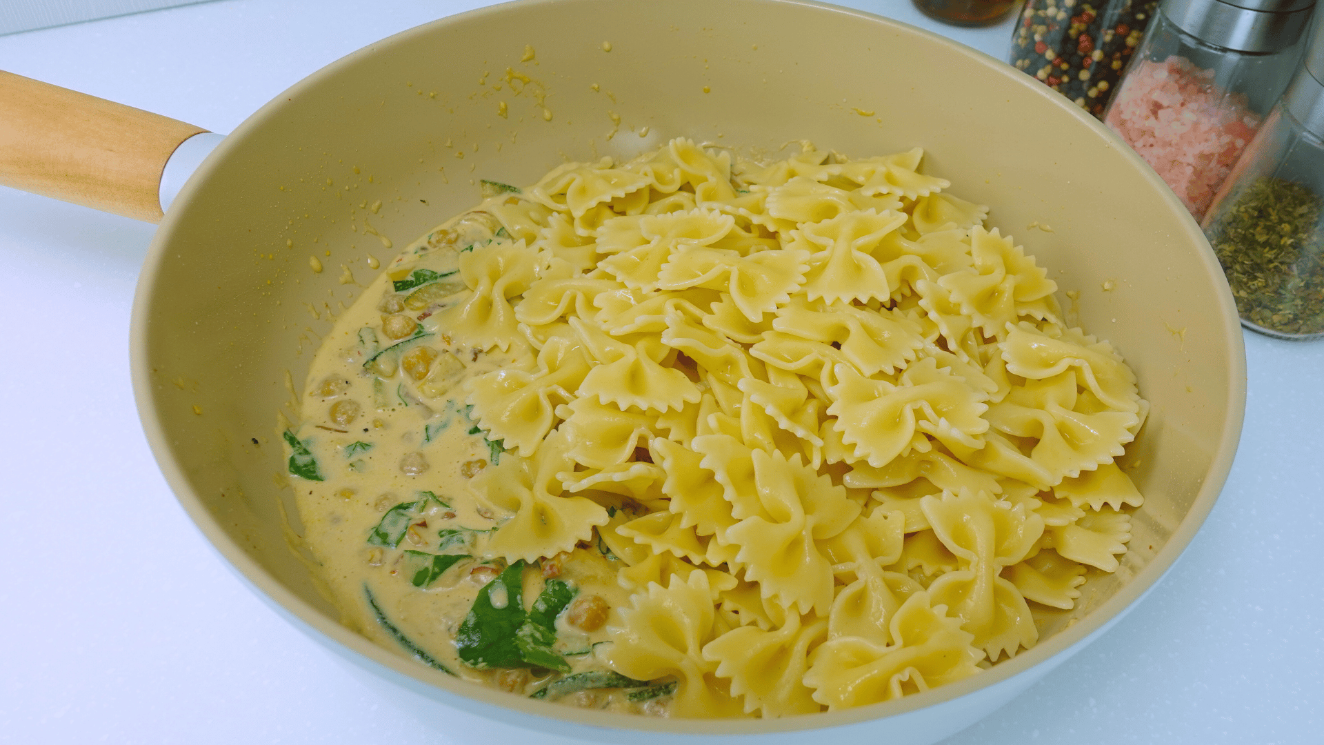 Mixing cooked pasta with creamy cashew sauce and chickpeas.