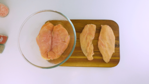 Raw chicken breasts on a cutting board.