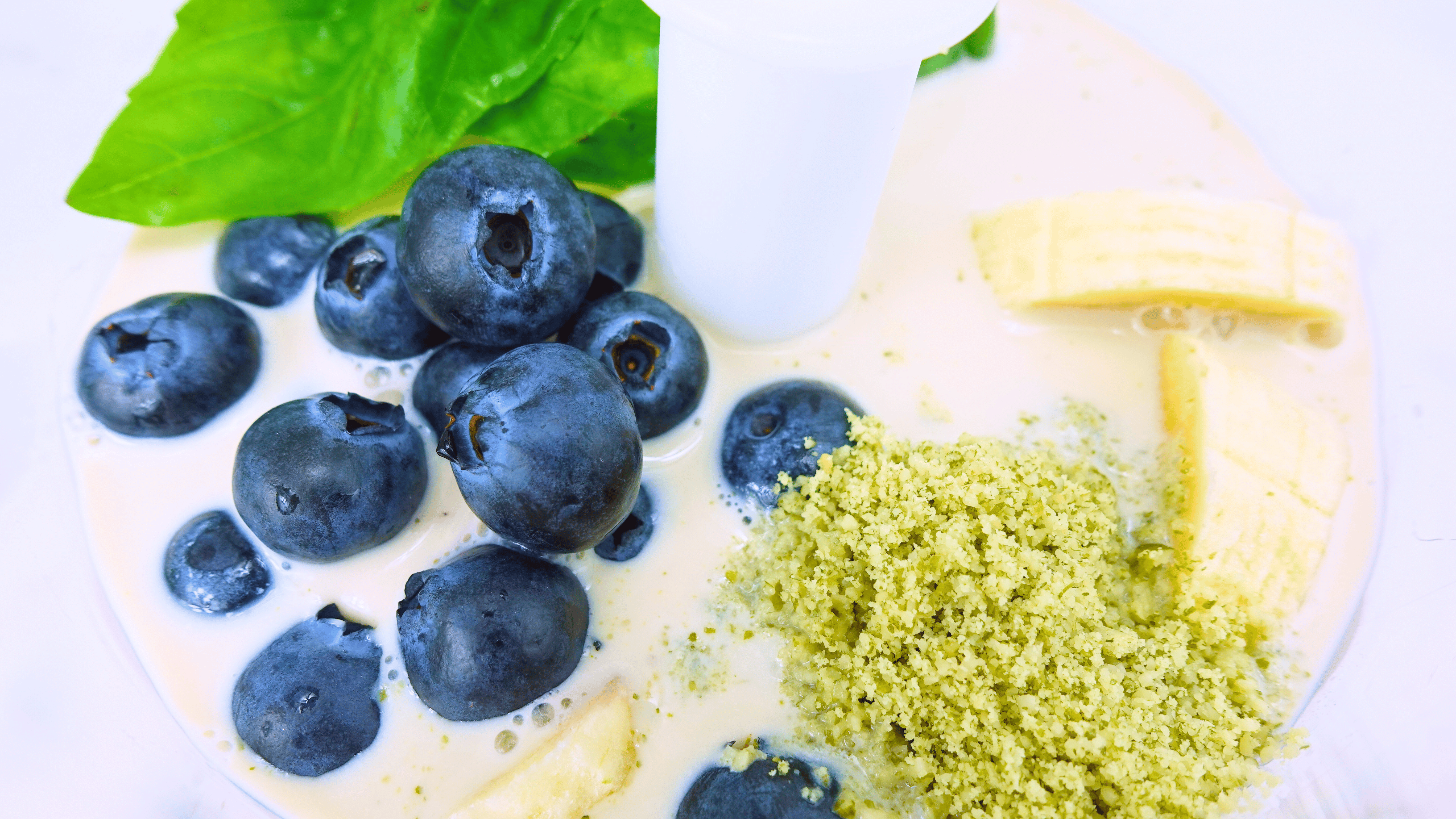 Close up photo of a Blender with blueberries and basil leaves