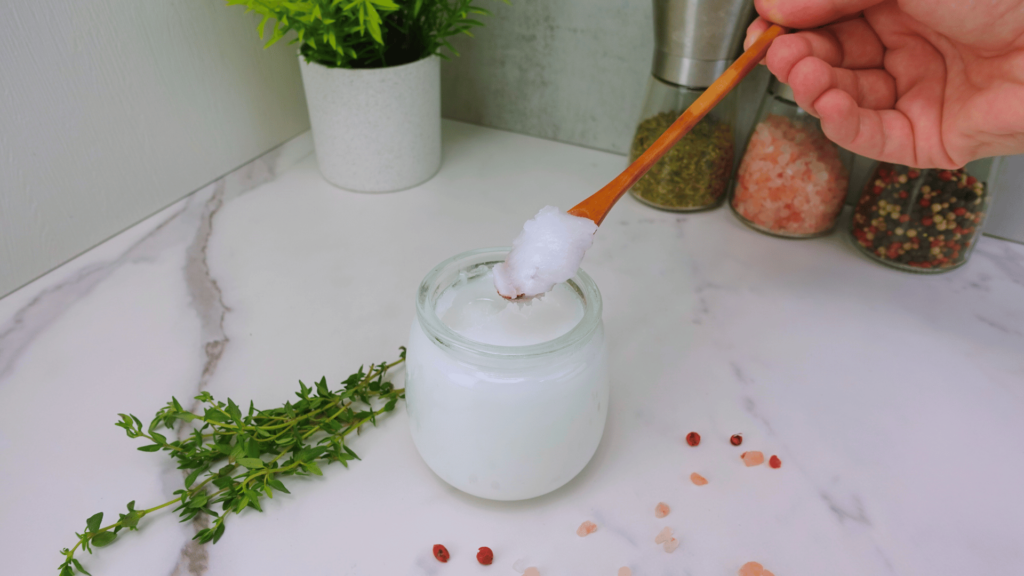 Coconut oil being scooped from a jar with a spoon.