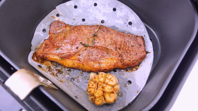 Cooked Porterhouse steak in the air fryer basket.