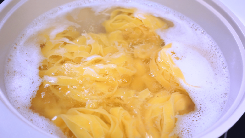 Cooking pasta in a pot, close-up top view.