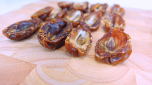 Pitted date halves on a wooden board.