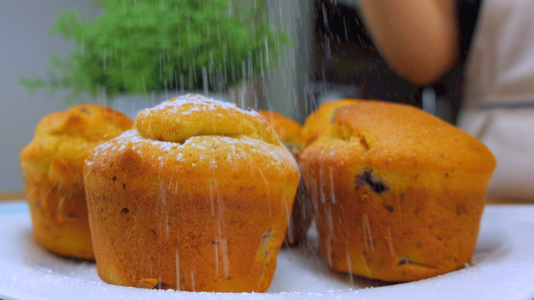 Sprinkling powdered sugar over muffins.