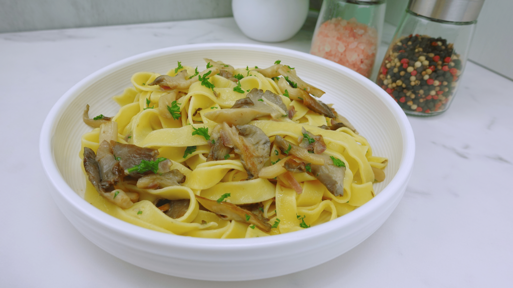 Finished garlic mushroom pasta in a white plate on the table.