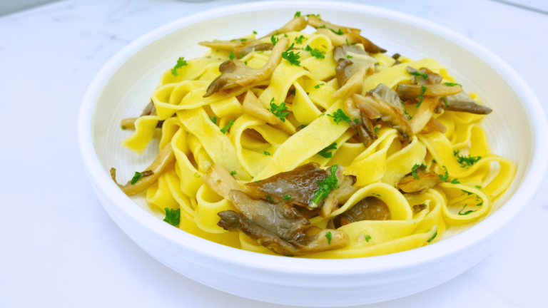 Finished garlic mushroom pasta in a white plate on the table.