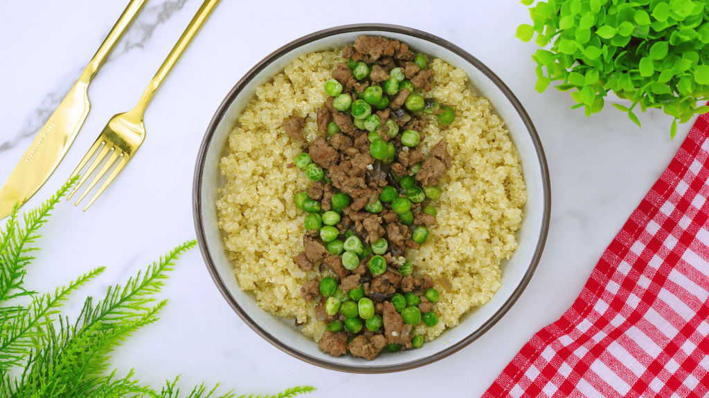 A table setting featuring a dish of ground beef and peas in the center.