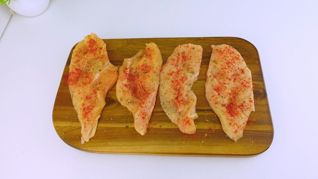 Top view of chicken breasts with paprika and Mediterranean herbs.