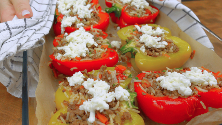 Close-up of vibrant bell peppers filled with seasoned chicken and melted mozzarella cheese.