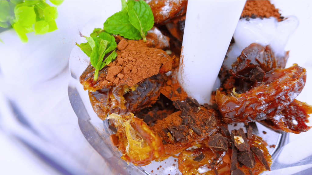 Close-up of cacao nibs truffles ingredients in a blender bowl.